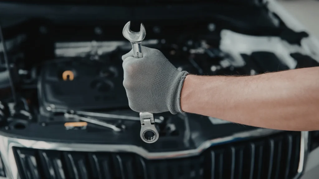 Mechanik podczas naprawy auta z kluczem